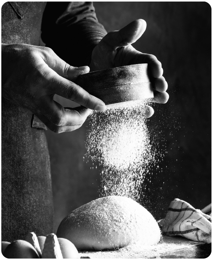 fotografia a blanco y negro espolvoreando azucar glass a masa de pan